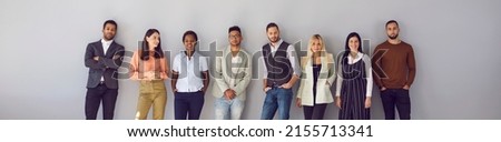 Young diverse fashion models posing against gray background. Banner with group portrait of confident young multi ethnic people in smart casual office wear standing in studio and leaning on grey wall Royalty-Free Stock Photo #2155713341