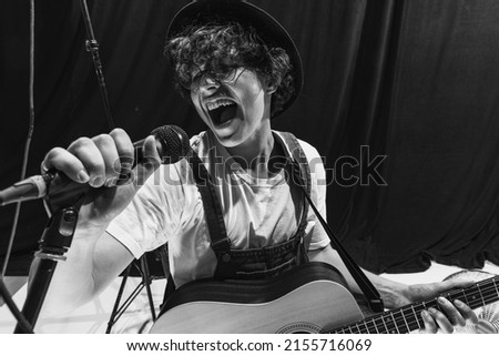 Rock music. Repetition of retro music band at music studio. Young musician playing acoustic guitar and singing. Rehearsal base. Concept of art, music, style and creation. Royalty-Free Stock Photo #2155716069
