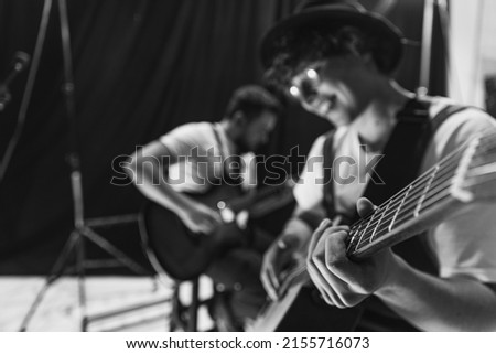Black and white image. Repetition of rock music band at music studio. Cropped image of electric and acoustic guitar players at concert. Rehearsal base Concept of art, music, style. Out of focus effect