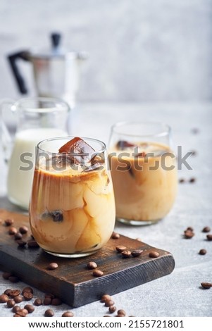 Ice coffee in glass. Ice coffee served in glass with coffee ice cubes and milk cream on table. Royalty-Free Stock Photo #2155721801