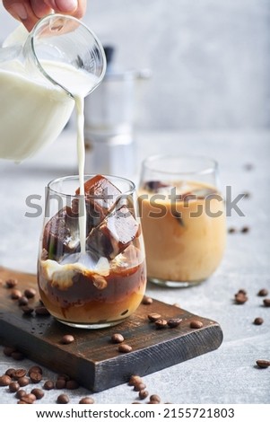 Ice coffee in glass. Ice coffee served in glass with coffee ice cubes and milk cream on table. Royalty-Free Stock Photo #2155721803