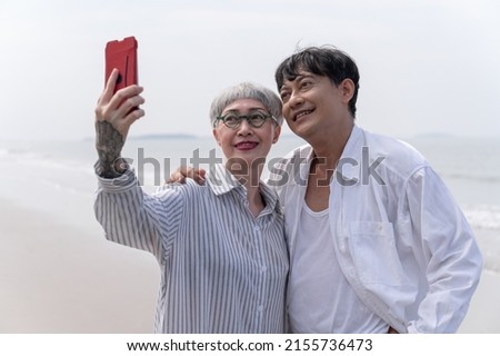 Happy senior couple selfie with smartphone on the beach