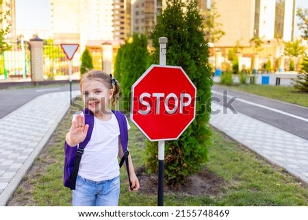 a schoolgirl girl with a STOP sign crosses the road or learns the rules of the road