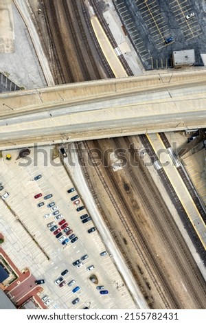 Overhead drone view of railroad, overpass, and parking lot in industrial part of urban environment