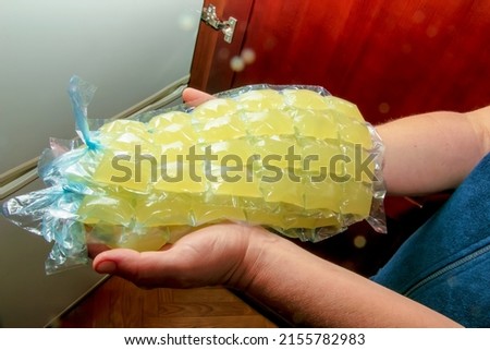 Women's hands hold bags for ice cubes with lemon juice. Freshly squeezed lemon juice is frozen in portions to make lemonade. Royalty-Free Stock Photo #2155782983