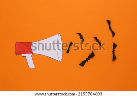 Paper cut cartoon megaphone with bats on orange background. Halloween concept