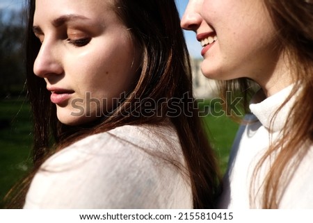 Portrait of two girls. Women in white dresses walking in the green sunny park