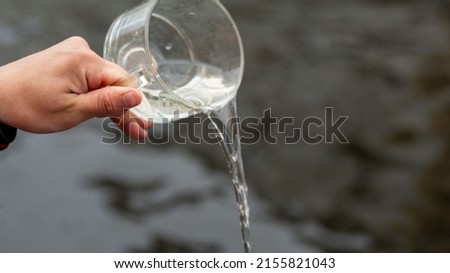 a person's hand holds a large mug from which water is poured out. background picture.