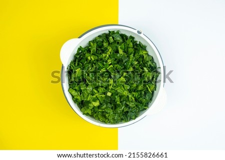 Lots of chopped spinach in white case, cooking and vegetable idea, healthy lifestyle, vegan life, yellow and white background, top view of spinach, copy space Royalty-Free Stock Photo #2155826661