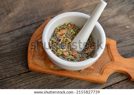 mortar with healing herbs, bouquet of daisy and clovers on wooden board, herbal medicine