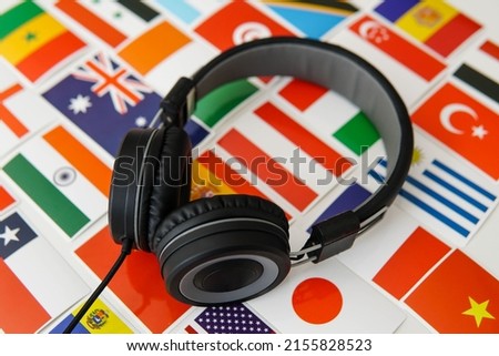 Learning foreign languages online. Headphones and countries flags on the background. Royalty-Free Stock Photo #2155828523