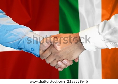 Business handshake on background of two flags. Men handshake on background of Ireland and Latvia flag. Support concept