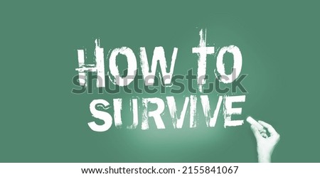 Blackboard with the text How to Survive and hand with yellow chalk. Survival in business in crisis times concept, avoid virus healthcare concept.