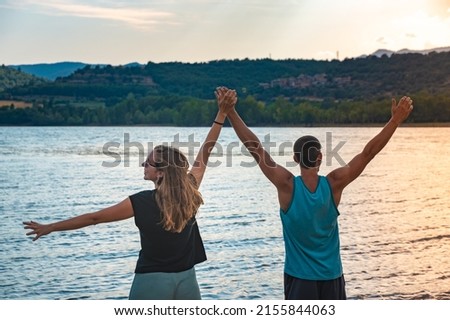 Young Attractive Couple open arms holding hands in a Beautiful Lake in summer during sunset. Discovery Travel love Destination Concept. Royalty-Free Stock Photo #2155844063