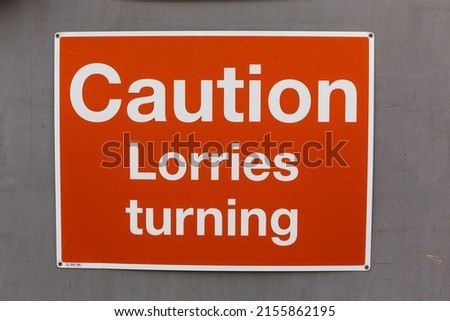 Caution lorries turning warning sign with white text on a red background