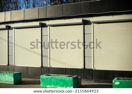 Building has closed windows. Shutters on store. Real estate sales office.