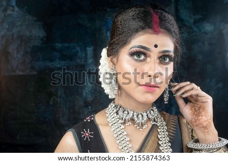 Portrait of a beautiful young Indian woman in traditional clothing and Indian accessories. Royalty-Free Stock Photo #2155874363