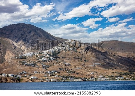 Serifos island Cyclades Greece. White building uphill Chora town and at the seaside, island port. Rippled Aegean Sea, cloud on blue sky.