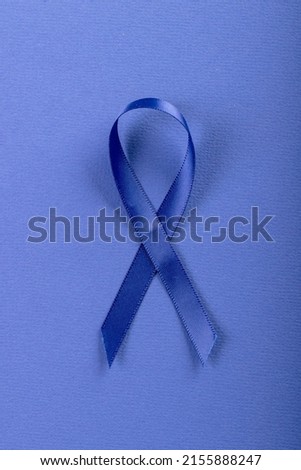 Close-up of blue stomach cancer awareness ribbon isolated against blue background, copy space. blue, stomach, cancer, medical, ribbon, awareness, support, healthcare and alertness concept.