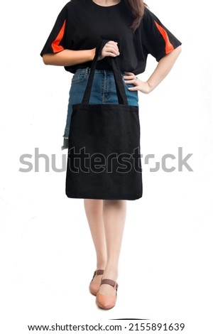 Girl holding fashion canvas eco-bag wearing skirt and t-shirt. White background. Stock photo.