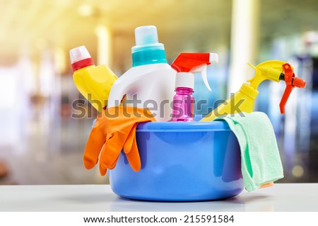 Basket with cleaning items on blurry background Royalty-Free Stock Photo #215591584