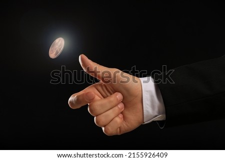 Man throwing coin on black background, closeup. Making decision Royalty-Free Stock Photo #2155926409