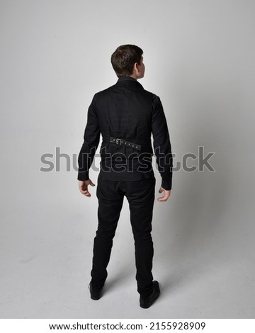 Full length portrait of  handsome brunette male model wearing black shirt and vest. Standing  Pose with gestural hands reaching out,   isolated on studio background.