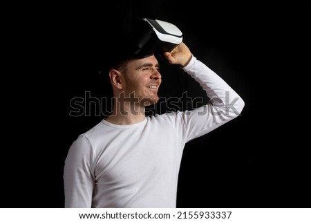 Contemporary young man experiencing virtual reality glasses in studio.Black background