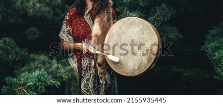 shamanic girl playing on shaman frame drum in the nature.