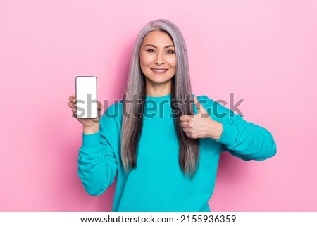 Portrait of positive friendly lady show thumb up empty space telephone display isolated on pink color background