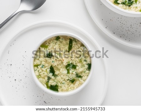 Homemade Italian soup Stracciatella with spinach. Egg drop soup in a white plates. Flat Lay. Horizontal. High key