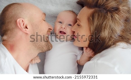 Happy parents with his newborn baby, top view. Happy family. Healthy newborn baby with mom and dad. Close up Faces of the mother, father and infant baby. Cute Infant boy and parents.