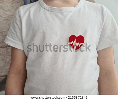 Child in white shirt with heart emblem on chest. Treatment of cardiac arrhythmia in children concept Royalty-Free Stock Photo #2155972843