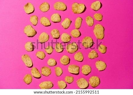 Top view of set of delicious and appetizing potato chips in rows isolated on pink background. Unhealthy eating and junk food. Crunchy snack for leisure. Studio shoot. Copy space. Nobody