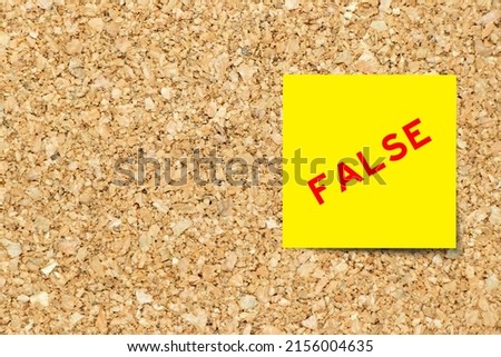 Yellow note paper with word false on cork board background with copy space Royalty-Free Stock Photo #2156004635