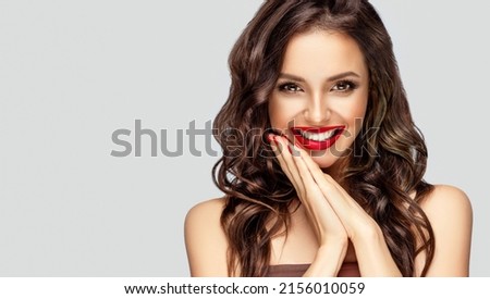 Beautiful laughing brunette model  girl  with long curly  hair . Smiling  woman hairstyle wavy curls . Red  lips and  nails manicure .    Fashion , beauty and make up portrait
