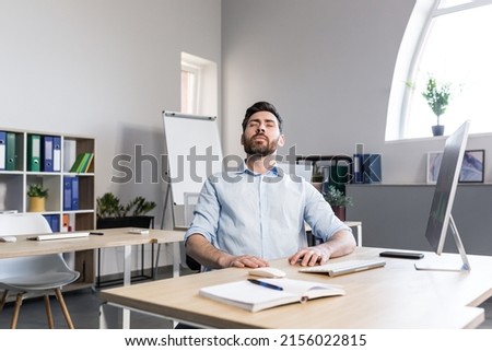 Businessman in the office with closed eyes performs breathing exercises, freelancer working on the computer Royalty-Free Stock Photo #2156022815