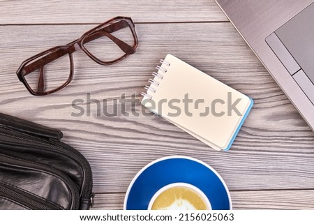 Blank notepad with glasses and cup of coffee on the table. Top view flat lay workdesk accesories.