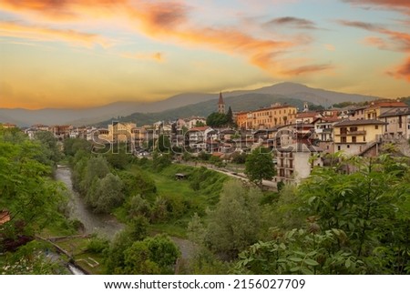 Dronero, Piedmont, Italy: View of the old village in Maira Valley with the river Maira. Landscape with colorful cloudy sunset sky
