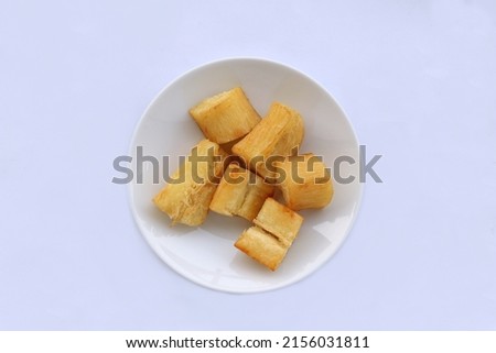 Indonesian traditional meal named "singkong goreng" i.e. fried slices cassava served on plate, isolated on white background