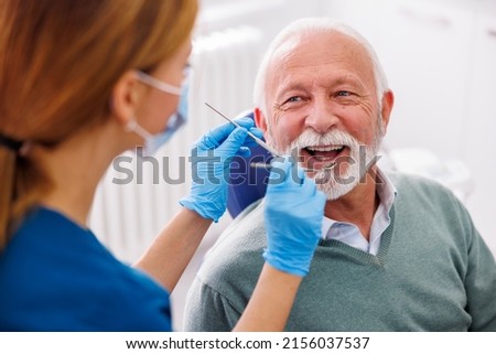 Doctor checking up patient's teeth at dentist office; senior man at dental checkup Royalty-Free Stock Photo #2156037537
