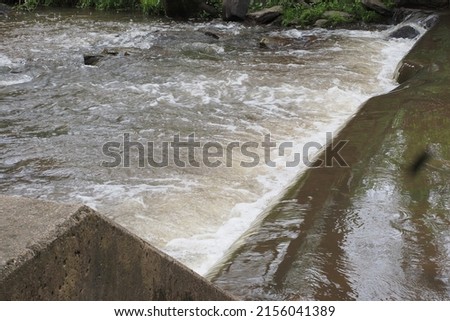 The water is flowing rapidly by the damn. Royalty-Free Stock Photo #2156041389