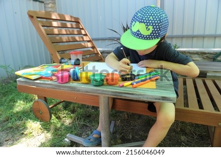 Child boy have a leisure drawing at the backyard outdoor, no face