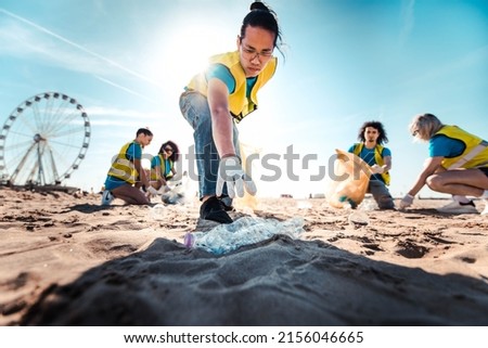 Group of eco volunteers picking up plastic trash on the beach - Activist people collecting garbage protecting the planet - Ocean pollution, environmental conservation and ecology concept Royalty-Free Stock Photo #2156046665