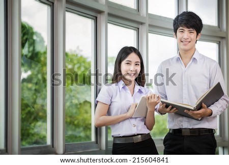 Asia students read a book and use smart phone in Library with uniform Royalty-Free Stock Photo #215604841
