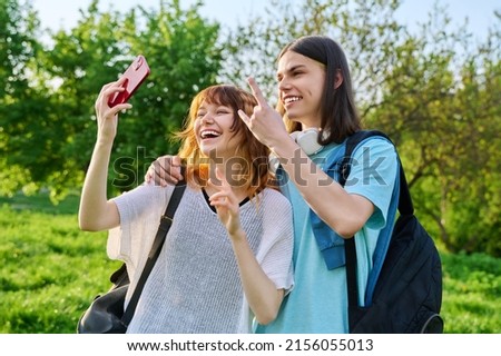 Young couple, laughing teenagers taking selfie photo on smartphone