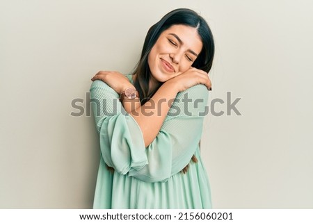 Young hispanic woman wearing casual clothes hugging oneself happy and positive, smiling confident. self love and self care  Royalty-Free Stock Photo #2156060201