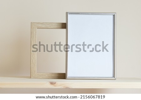 Simple composition with two frames silver and wooden frames on yellow background.