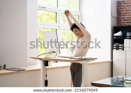 Worker Stretch Exercise At Stand Desk In Office Royalty-Free Stock Photo #2156079049