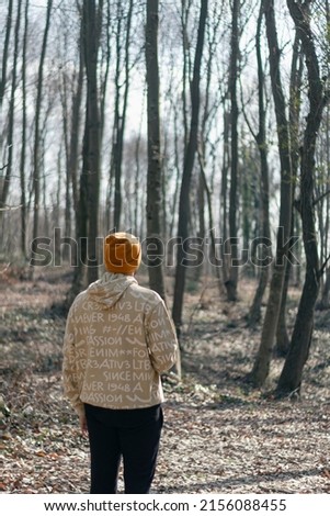 Back view of young man with hat walking in forest. Unrecognizable person. Travel, sport and hiking concept.
